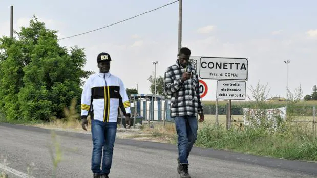 Los migrantes caminan por un sendero cerca del centro de acogida de Cona, cerca de Padua