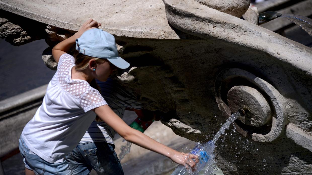 Una persona llena una botella de agua de la fuente de la Piazza di Spagna de Roma