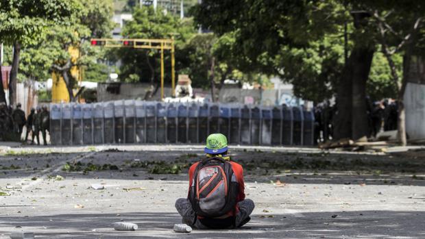 Un manifestante permanece sentado en frente de miembros de la Guardia Nacional Bolivariana (GNB) durante una de las protestas en el marco de la huelga general