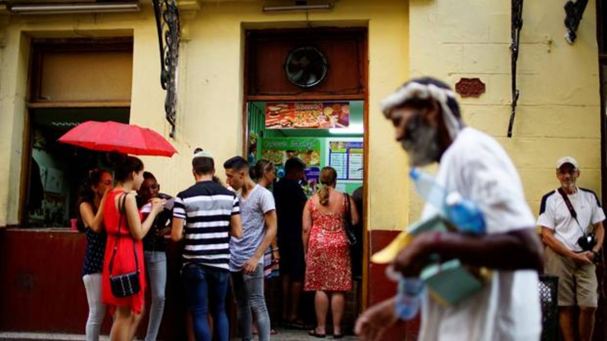 Un grupo de personas, junto a la puerta de un restaurante privado en La Habana