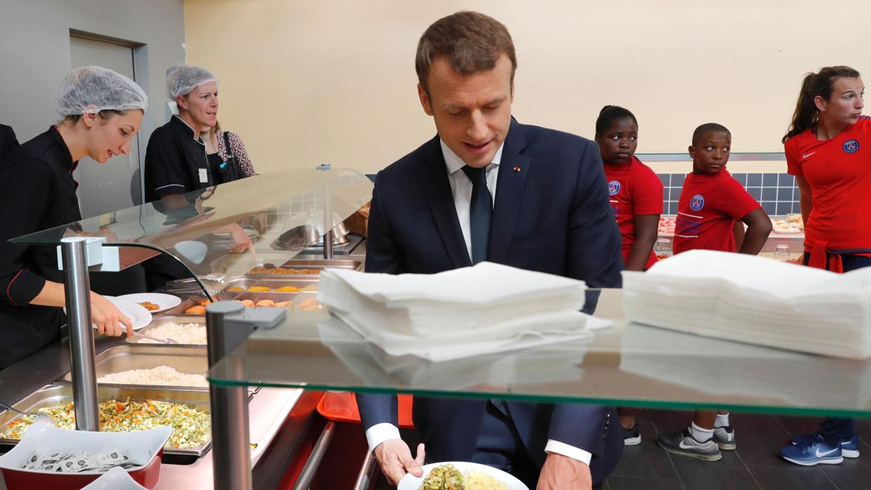 El presidente francés Emmanuel Macron (C) hace cola en un restaurante antes de compartir un almuerzo con los niños de la Fondation París Saint-Germain