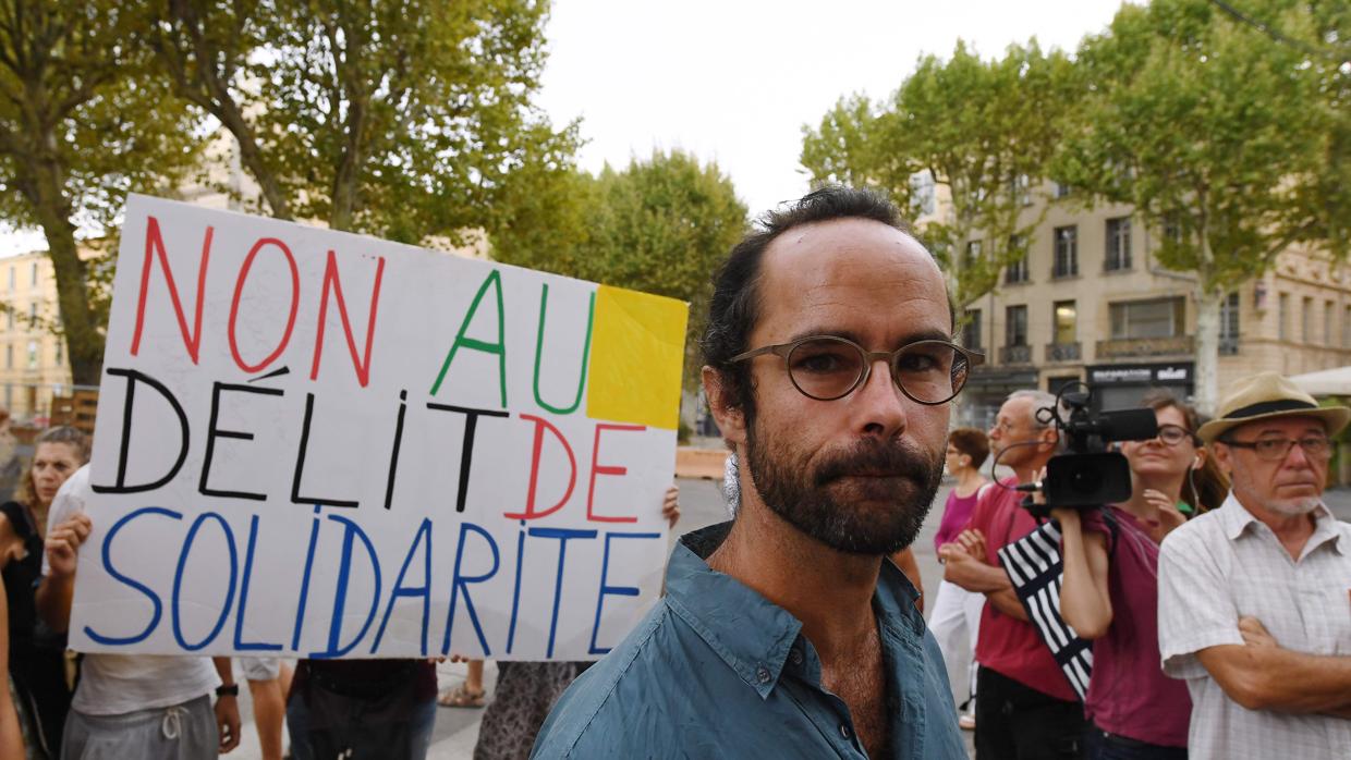 El agricultor francés Cedric Herrou, a la entrada del palacio de justicia en Aix-en-Provence cerca de un letrero que dice "No al crimen de solidaridad"