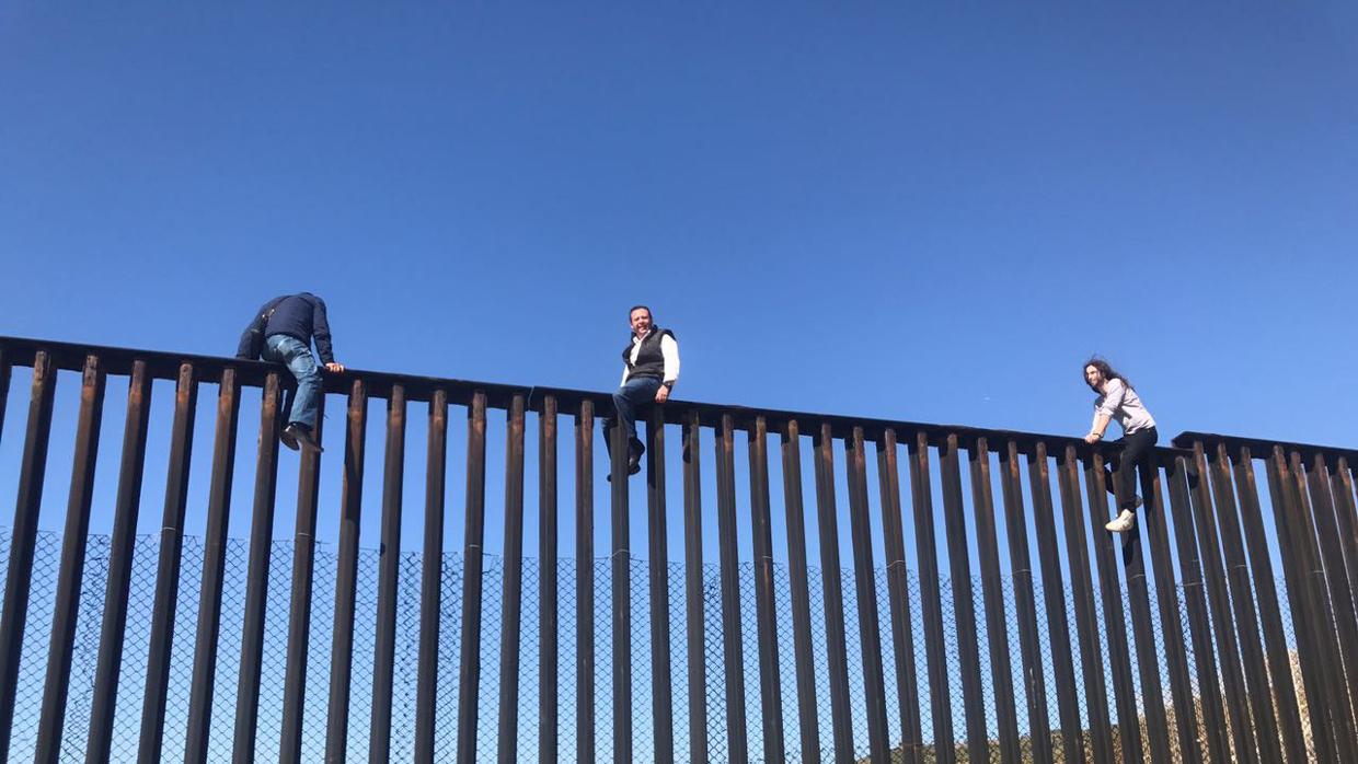 El diputado mexicano Braulio Guerra (c), trepó a lo alto de la valla fronteriza en Tijuana para protestar contra las pretensiones de Trump