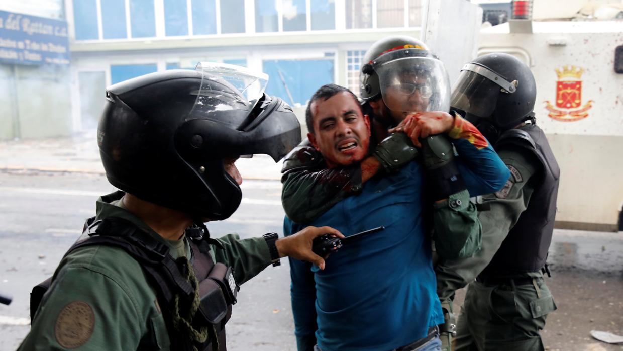 Un grupo de policías bolivarianos detienen a un joven en el transcurso de una manifestación