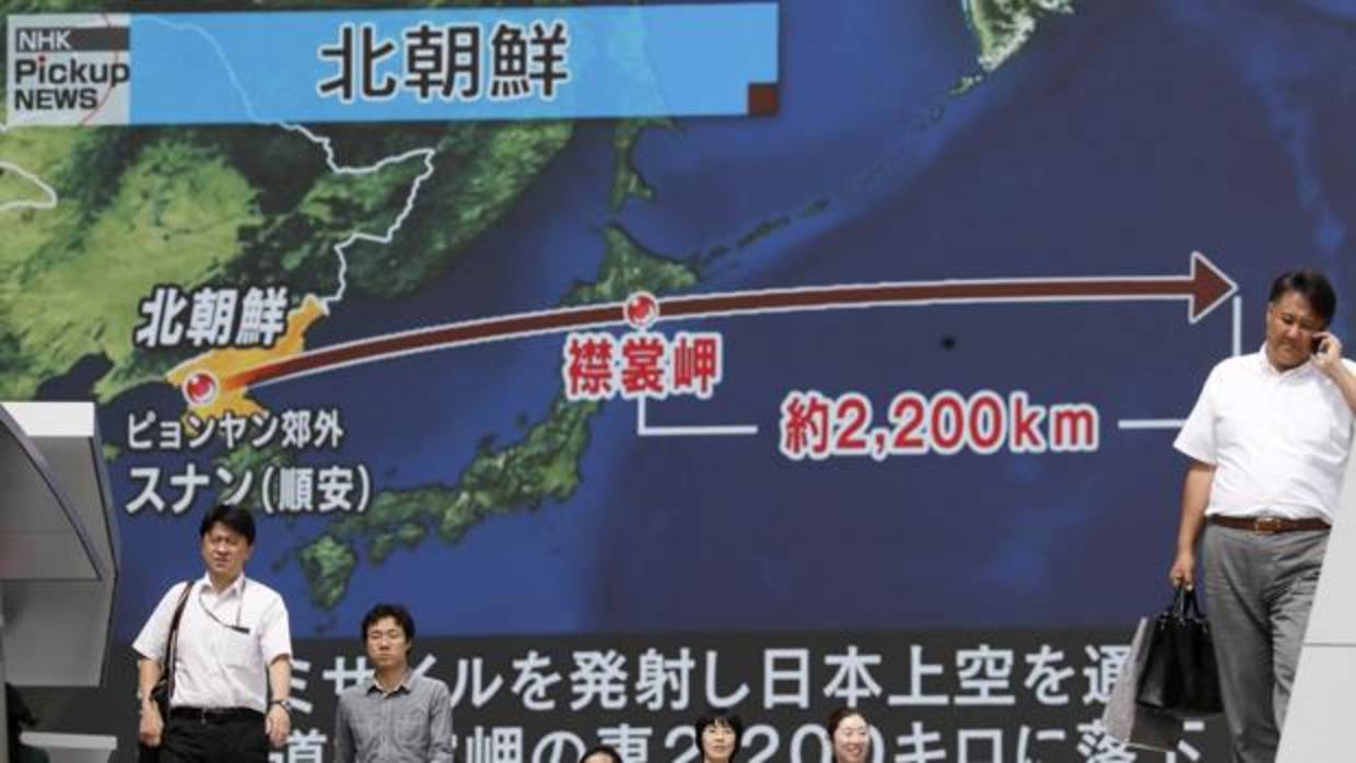 Japoneses caminan bajo un monitor a gran escala que muestra el vuelo de un misil balístico norcoreano