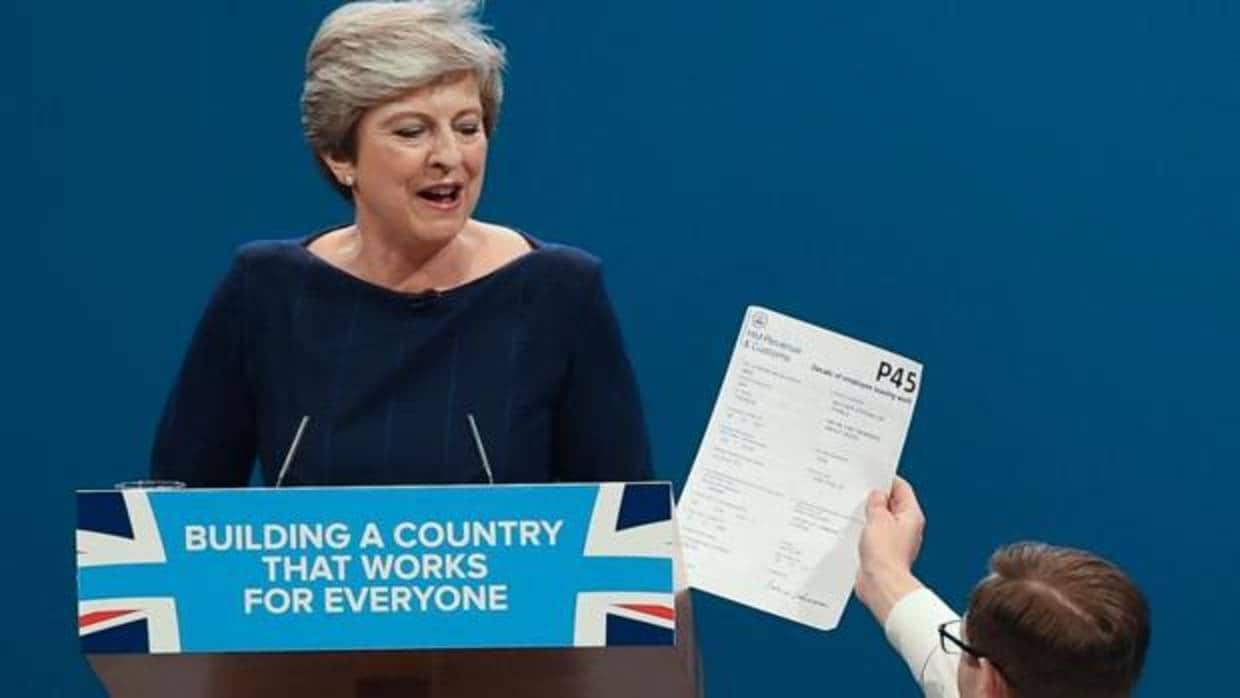 Un manifestante interrumpe el discurso de Theresa May en la convención anual tory y le entrega un ejemplar del formulario P45 (carta de despido para los trabajadores), este miércoles en Mánchester