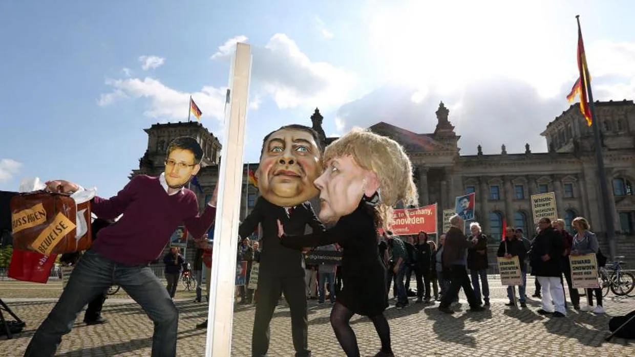 Activistas disfrazados de Edward Snowden (i) ,Angela Merkel (d) y Sigmar Gabriel, junto al Reichstag en Berlín