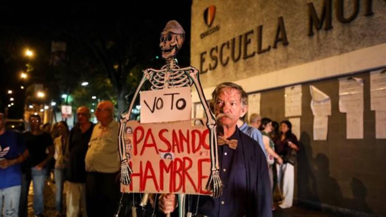 Un hombre camina con un esqueleto a modo de protesta durante el cierre de las mesas de votación hoy, domingo 15 de octubre de 2017, en un centro electoral de Caracas (Venezuela). Este domingo la oposición y el chavismo se midieron por las 23 gobernaciones del país en unos comicios en los que estuvieron llamados a participar poco más de 18 millones de votantes