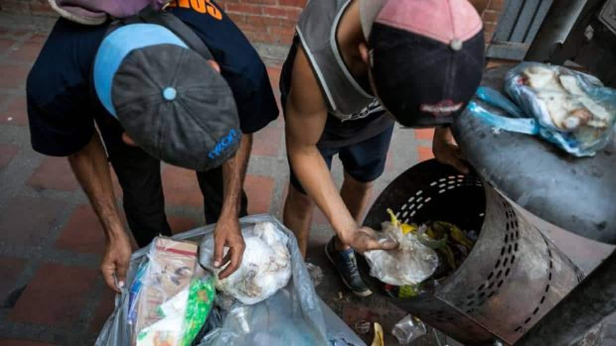 Dos niños hurgan en la basura en las calles de Caracas en busca de comida