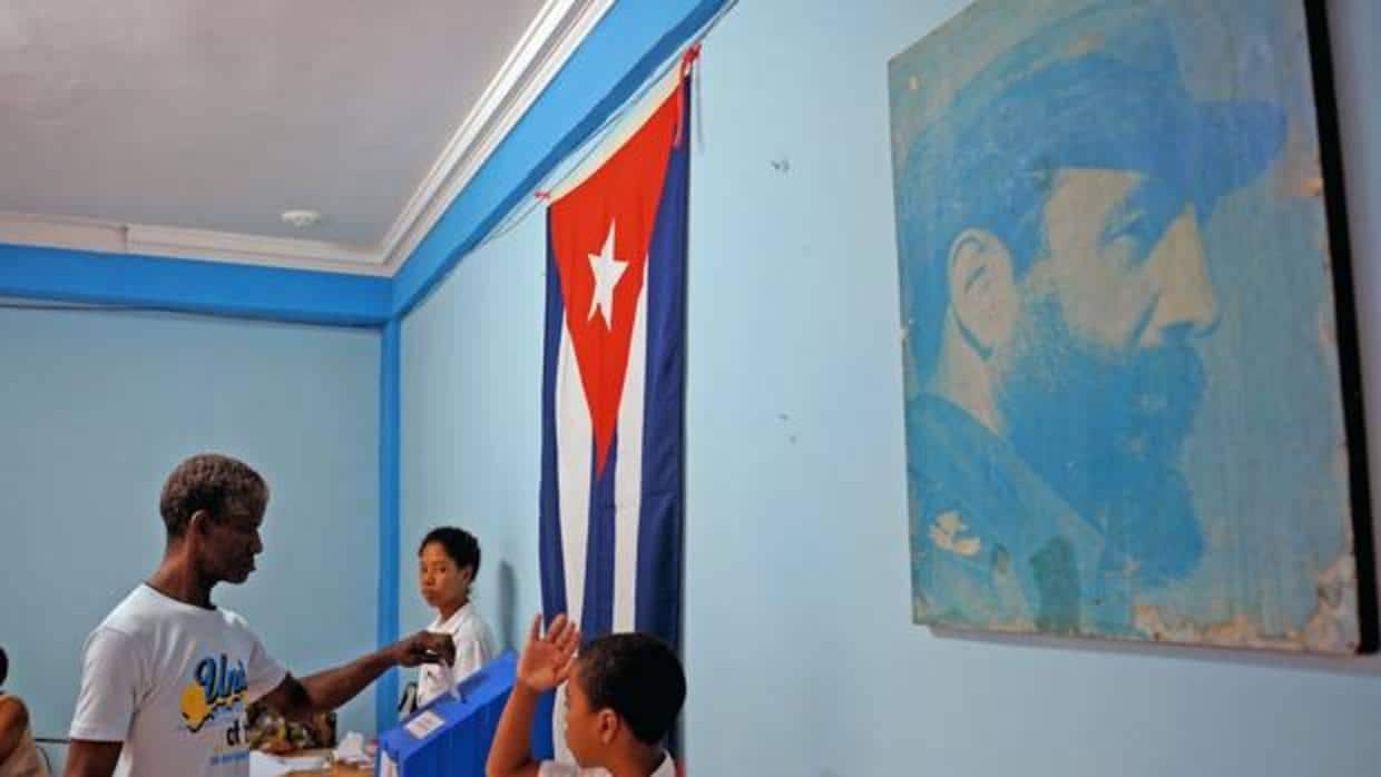 Un votante deposita su papeleta ante la imagen de Fidel Castro en un colegio de la Habana Vieja
