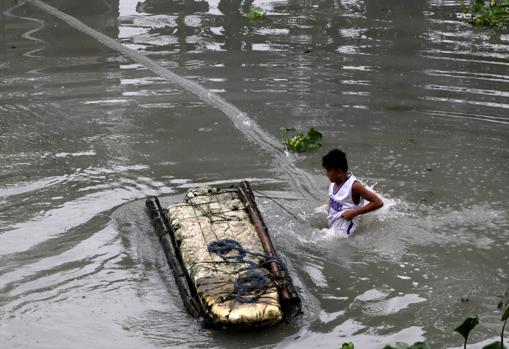 Un niño camina por una calle inundada de Taguig City, al sur de Manila (Filipinas)