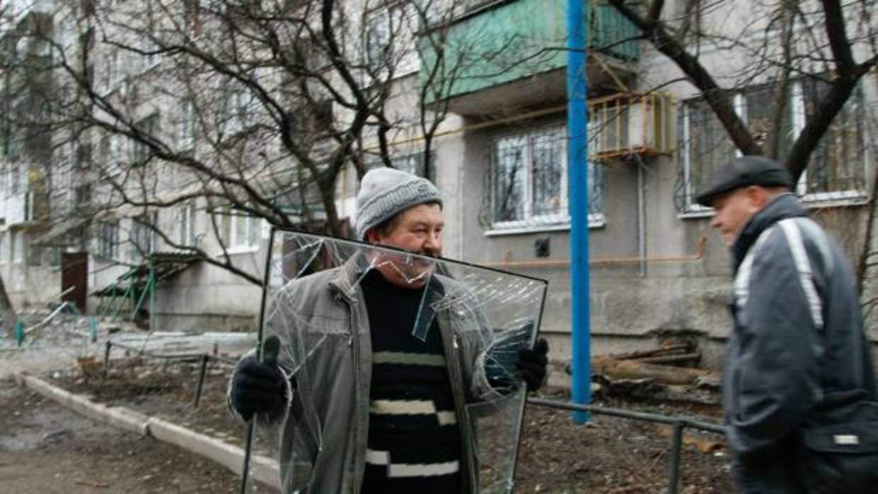 Un hombre carga con una ventana rota después de que su vivienda fuera alcanzada por el bombardeo de rebeldes pro-rusos en la ciudad controlada de Yasinovátaya, en Donetsk