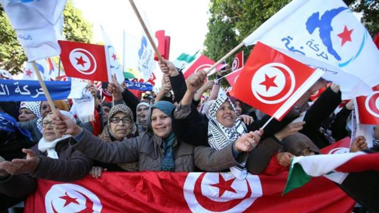 Mujeres tunecinas enarbolan la bandera nacional durante una marcha para conmemorar el 7º aniversario del fin de la dictadura de Zine El Abinide Ben Ali, este domingo en la capital