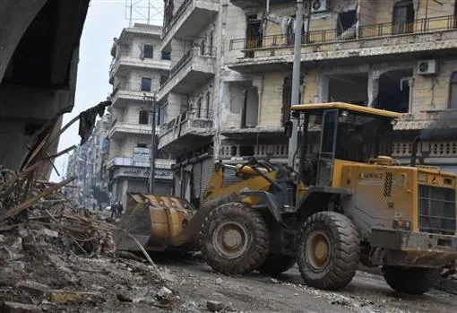 Una excavadora trabaja en un barrio de Alepo retirando escombros