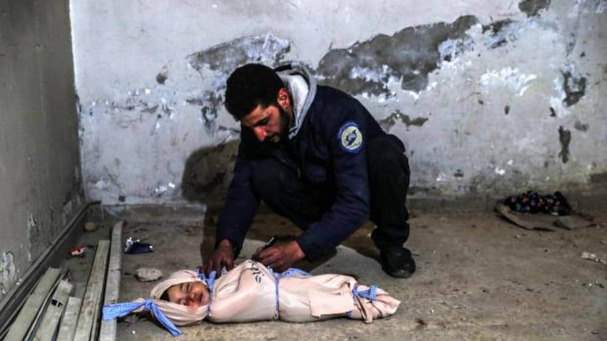 Un voluntario de los cascos blancos escribe información en el cuerpo sin vida de un niño muerto tras un bombardeo en Guta Oriental