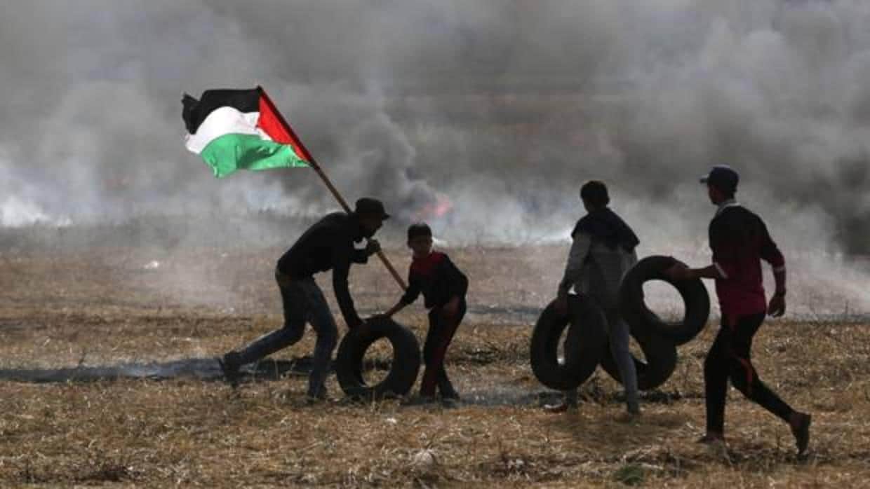 Palestinos con neumáticos para quemarlos durante los enfrentamientos con militares israelíes este jueves