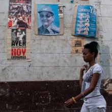 Una mujer camina junto a un cartel de Raúl Castro en La Habana