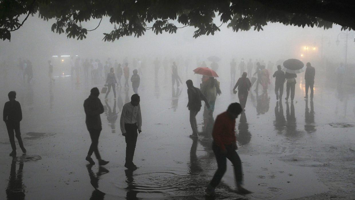 Personas caminan debajo de la tormenta en India