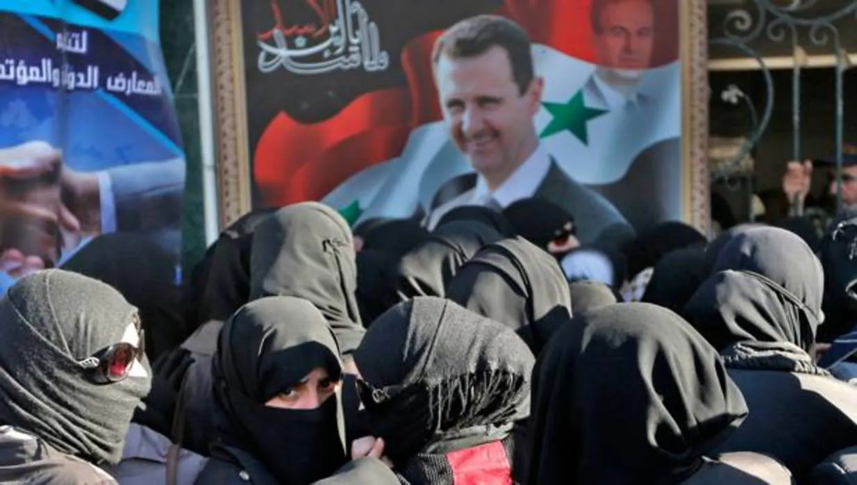 Un grupo de mujeres sirias junto a un cartel del presidente Al Assad