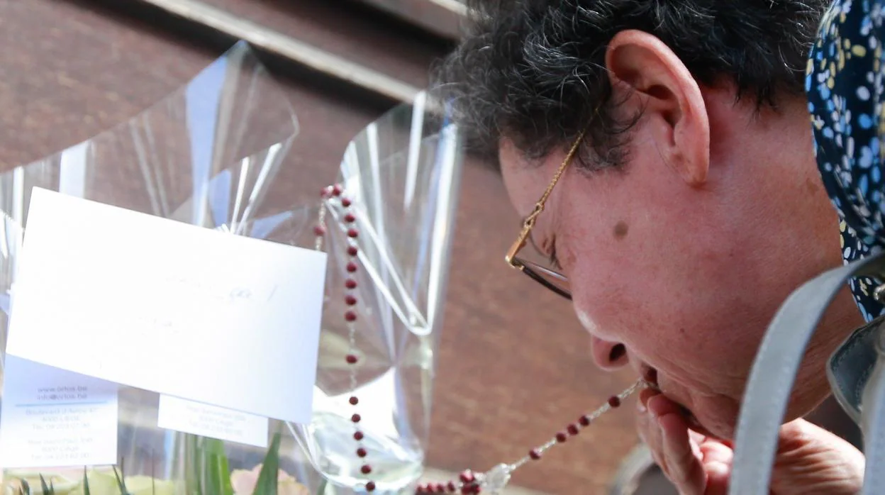 Bernadette Hennart, madre de una agente de policía belga asesinada ayer durante un tiroteo, besa un rosario mientras rinde tributo a su hija ante el Cafe 'Les Augustins'