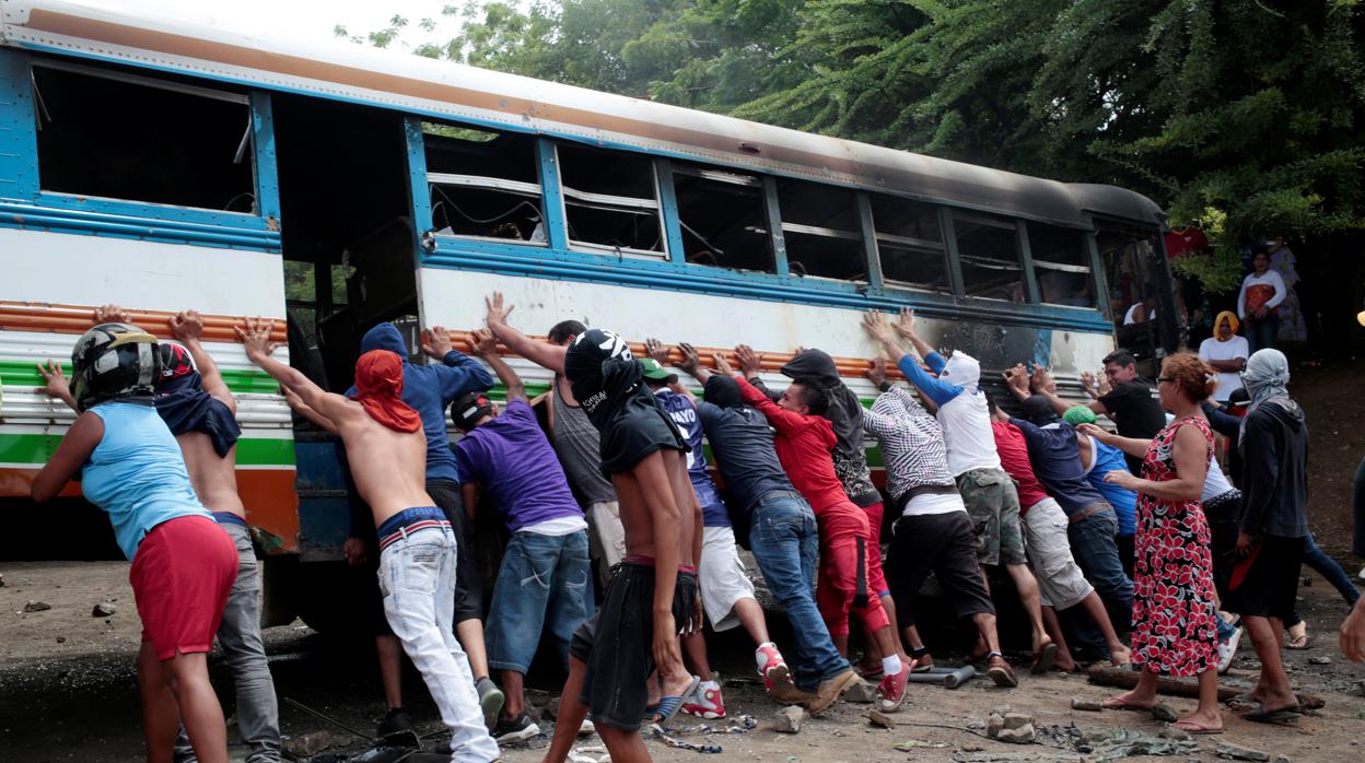 Manifestantes colocan un autobus incendiado como barricada