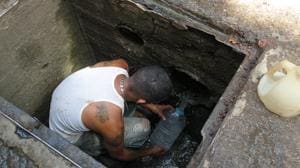 Un hombre se mete dentro de una alcantarilla para recoger agua limpia