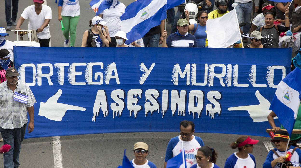 Manifestantes sostienen un cartel en contra de la pareja presidencial Ortega-Murillo