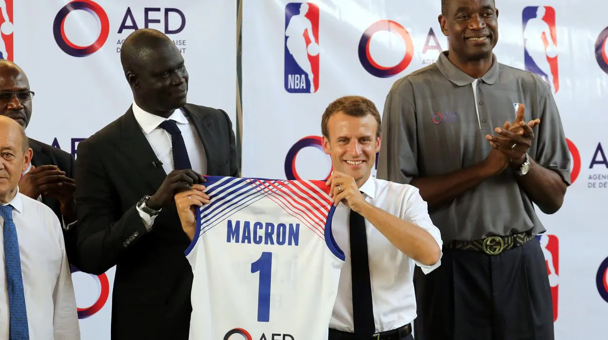 El presidente de Francia, Emmanuel Macron, sostiene una camiseta de baloncesto con su nombre