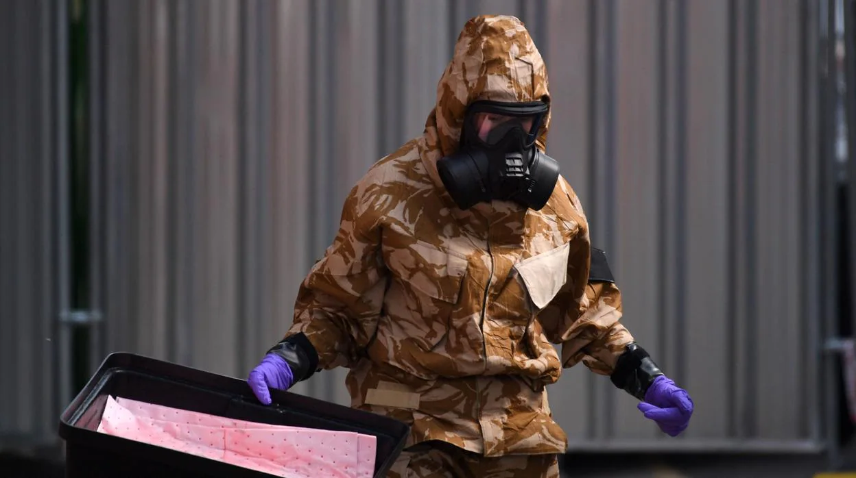 Un investigador que lleva un traje de protección camuflado, guantes y una máscara de gas trabaja en el caso
