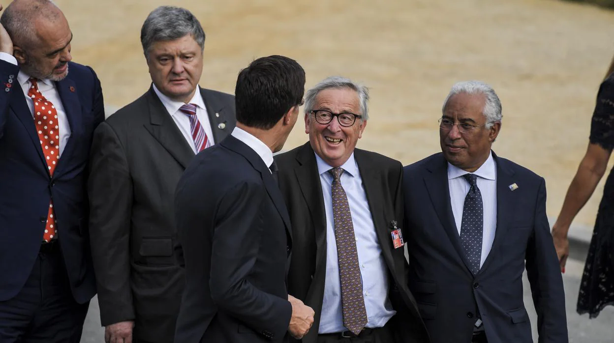 El presidente de la Comisión Europea, Jean-Claude Juncker, habla con varios mandatarios a su llegada a la cena de líderes este miércoles durante la cumbre de la OTAN