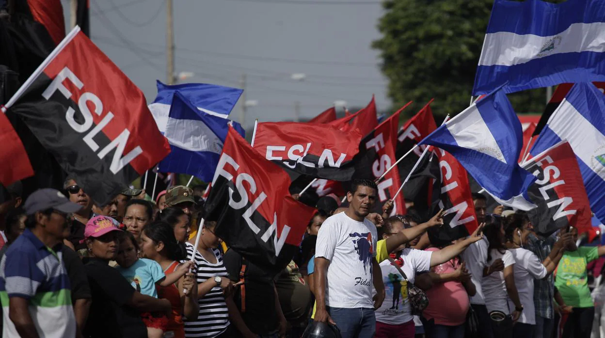 Un grupo de personas con banderas participa en una actividad conmemorativa al "repliegue táctico" de los sandinistas