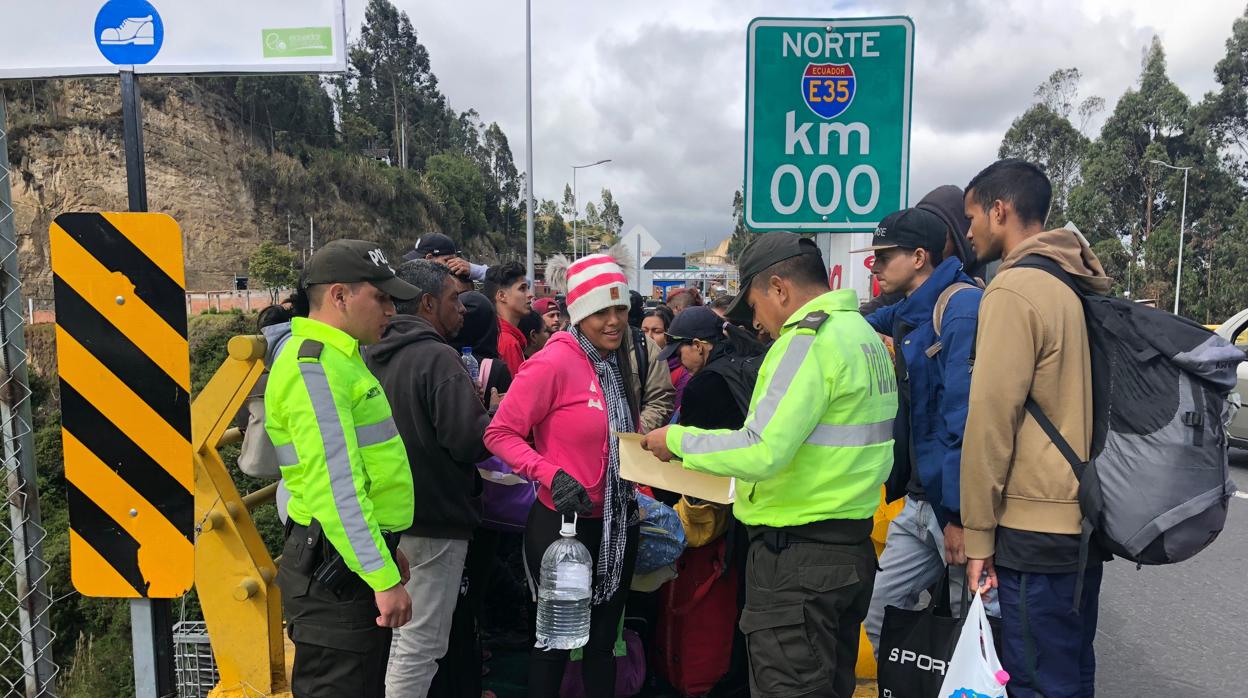 Policías ecuatorianos controlan una fila de emigrantes venezolanos en Ecuador