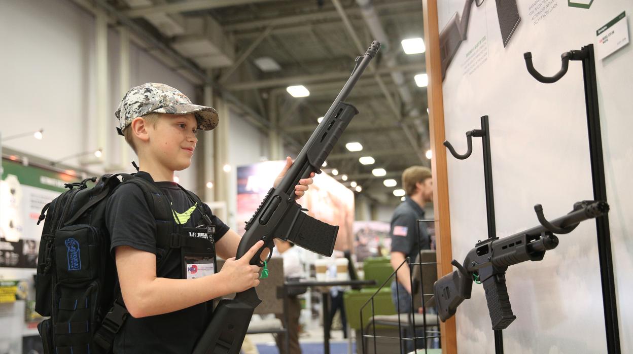 Blaise Maliskey, de 11 años, prueba un arma de fuego en una sala de exhibición en la convención anual de la NRA