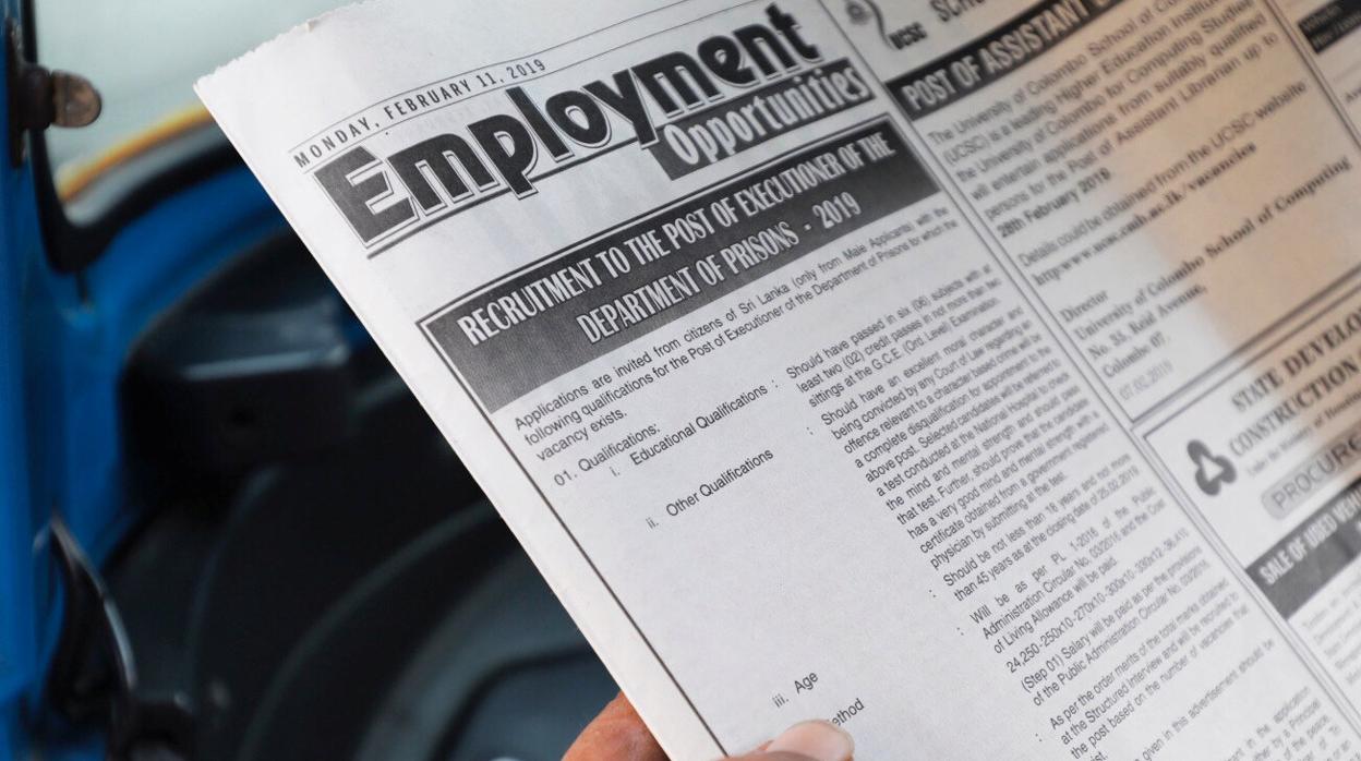 Un hombre lee el anuncio de la vacante de verdugos en un periódico local