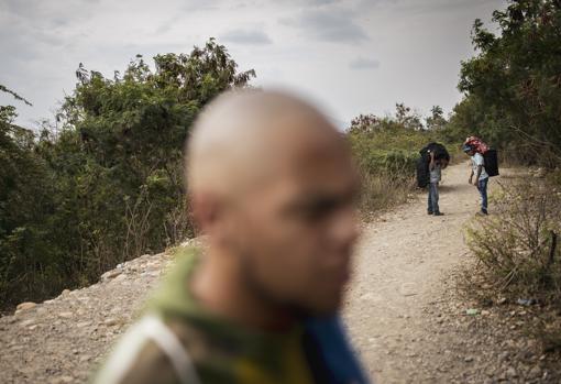 Un grupo de emigrantes venezolanos cruzan ilegalmente a Colombia por una «trocha» controlada por la guerrilla del ELN junto a la Guardia Nacional Bolivariana