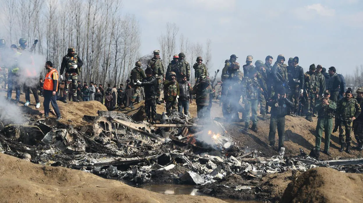 Soldados indios y observadores de Kashmiri se paran cerca de los restos de un avión de la Fuerza Aérea de la India