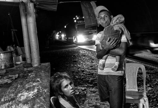 Una pareja de venezolanos descansan exhaustos con su bebé en un albergue