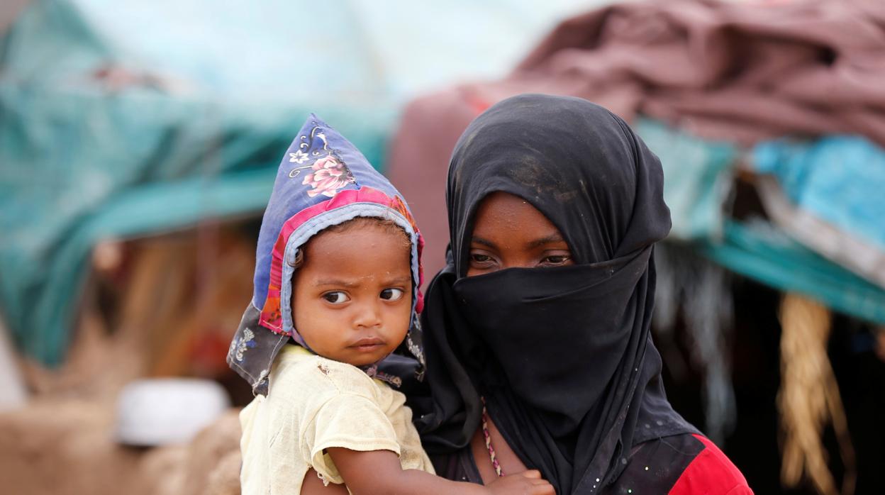 Una niña transporta a un niño en un campamento para desplazados en Yemen