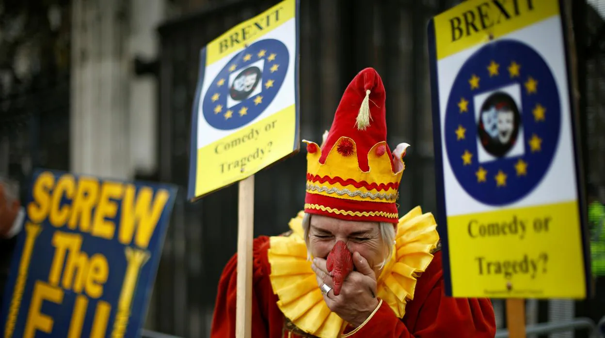 Un partidario de la UE vestido de bufón junto a un cartel de manifestantes anti-UE