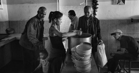 Una voluntaria sirve los platos de comida a los beneficiarios del comedor