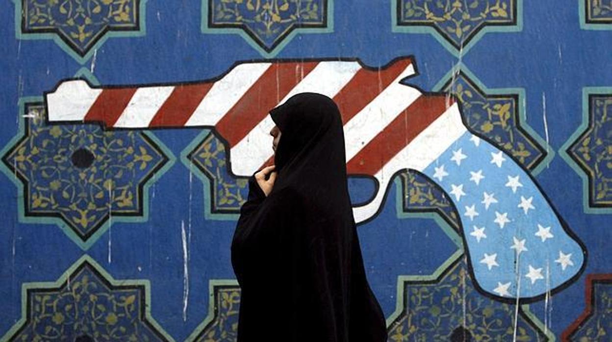 Una mujer iraní pasa frente a un mural antiamericano en Teherán