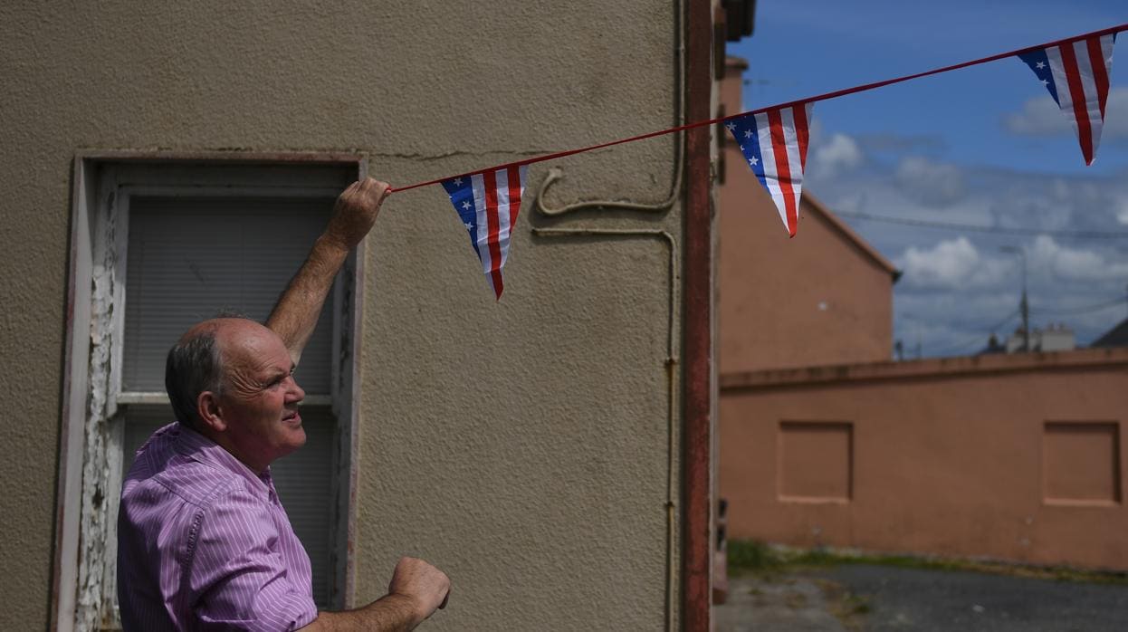 Un hombre coloca banderines con los colores de Estados Unidos en Doonbeg (Irlanda)