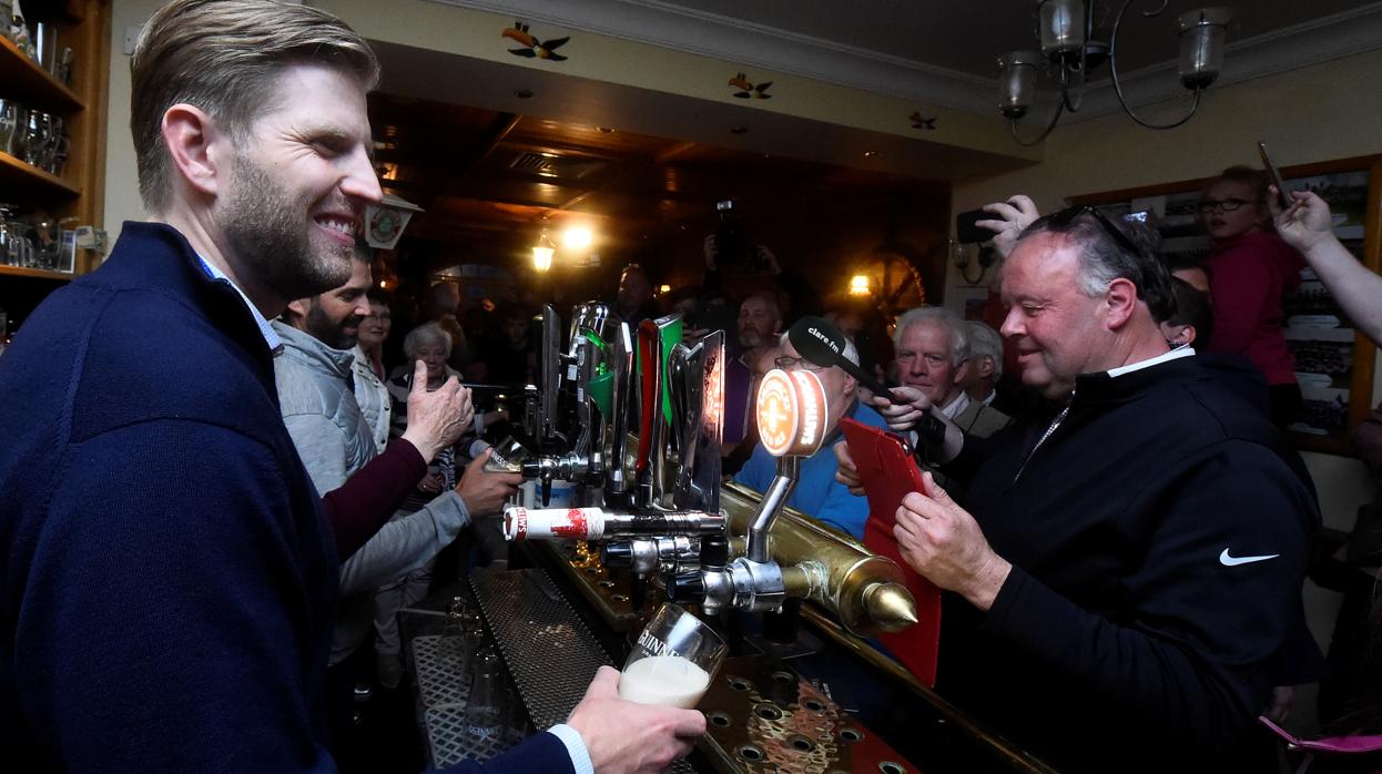 Eric Trump y su hermano Donald Jr. (al fondo) sirven cerveza en un pub de Doonbeg (Irlanda)