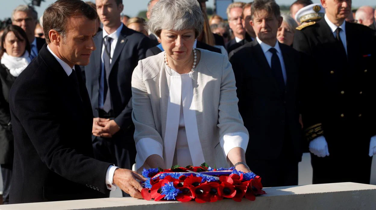 Emmanuel Macron y Theresa May realizan una ofrenda floral durante la colocación de la primera piedra de un monumento británico