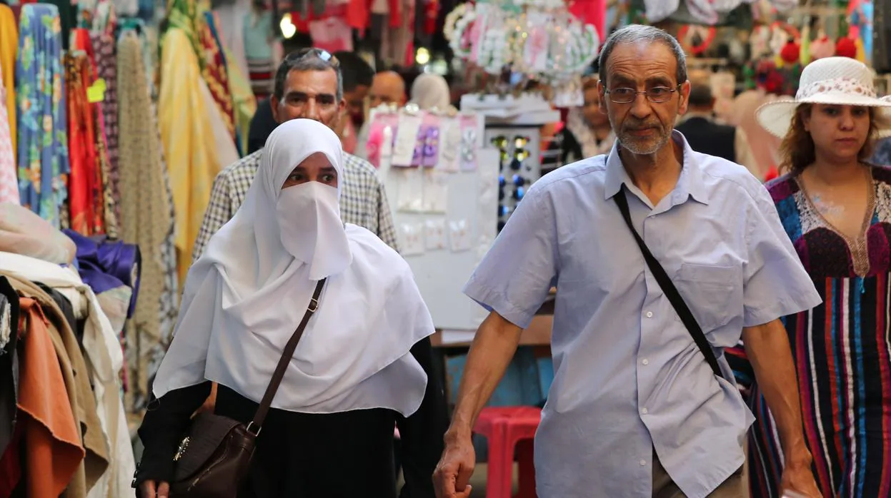 Una mujer con el rostro cubierto con un velo camina por la ciudad vieja de Túnez