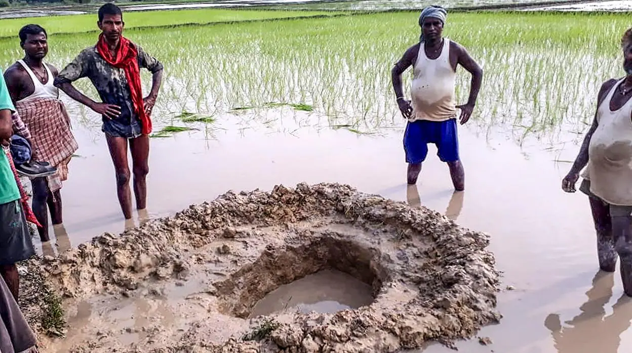 Habitantes del pueblo de Mahadeva posan al lado del cráter creado por el aterrizaje del supuesto meteorito