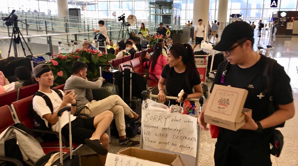 Cheung (en el centro) reparte pasteles y agua entre los pasajeros atrapados en el aeropuerto de Hong Kong por los vuelos cancelados por las protestas