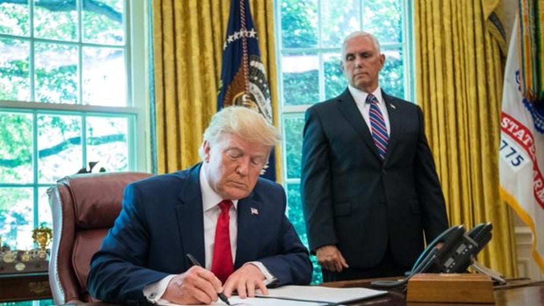 El presidente de Estados Unidos, Donald Trump, firma frente al vicepresidente, Mike Pence