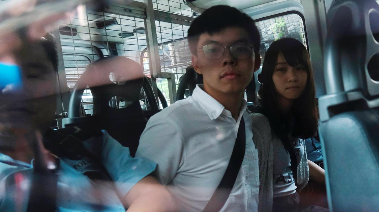 Los activistas Joshua Wong y Agnes Chow, detenidos en un furgón policial