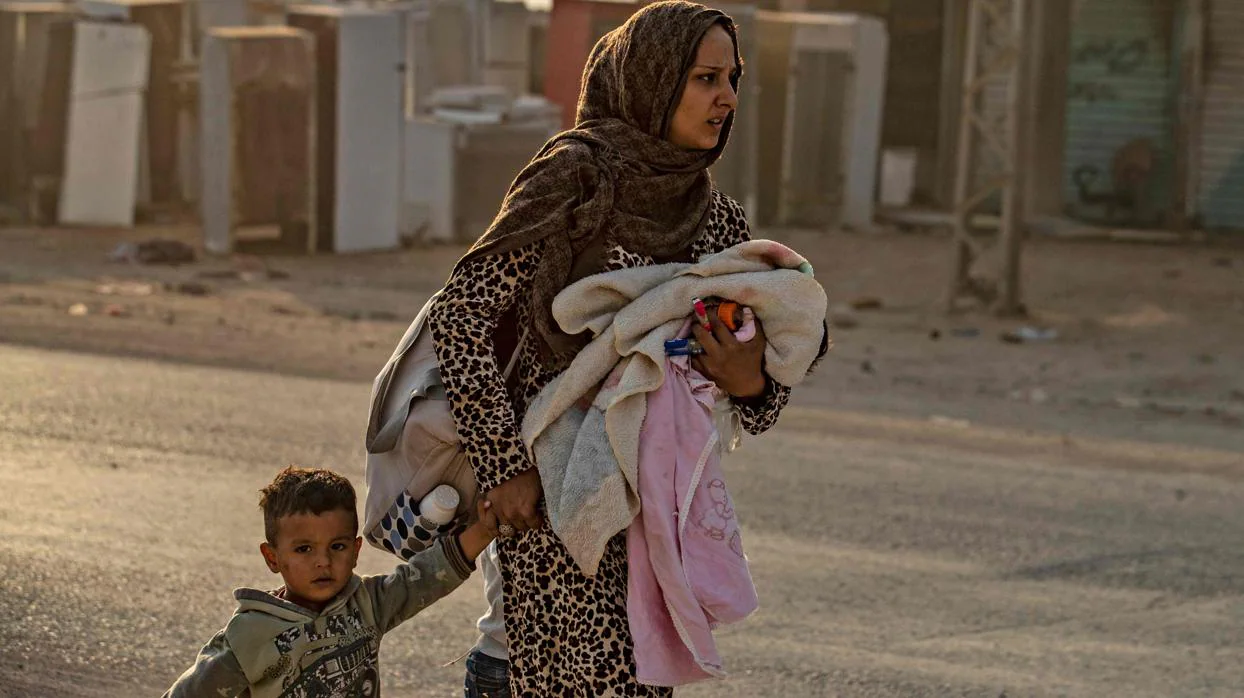 Una mujer huye con sus hijos de los bombardeos turcos en Ras al Ain